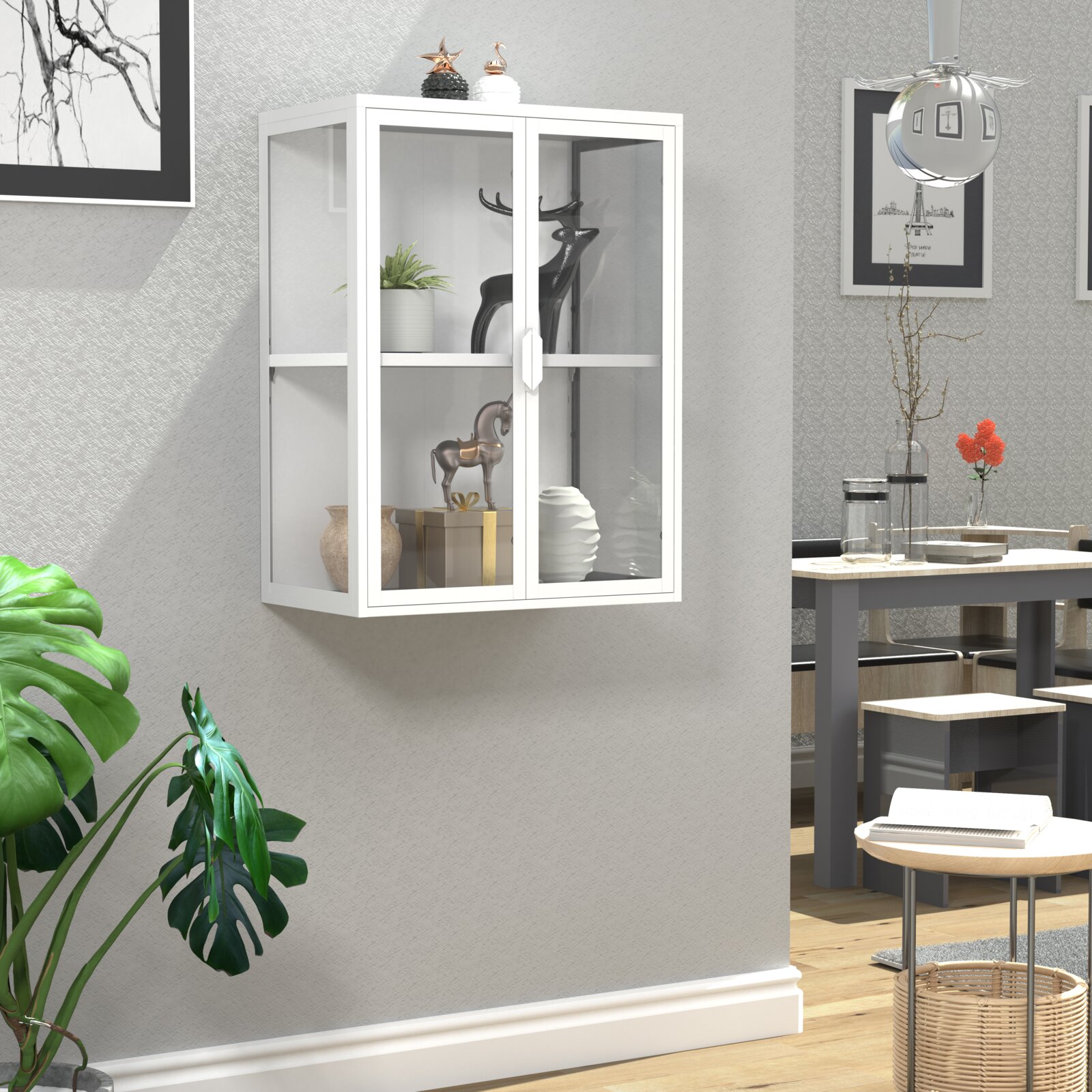 Weiße, wandmontierte Vitrine mit zwei Glastüren und Griffen, frontal aus leicht schräger Perspektive im Wohnraum, dekoriert mit Pflanze, Vasen und Figuren