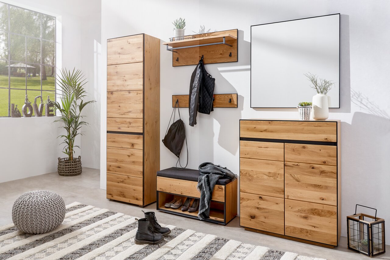 Moderne houten garderobecombinatie met schoenenkast, spiegel en garderobepaneel in een lichte ruimte, gezien vanaf de zijkant.