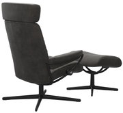 Achterkant van een fauteuil met hoofdsteun en bijpassende voetenbank, bekleed met donkere stof, op een zwart draaipootonderstel.