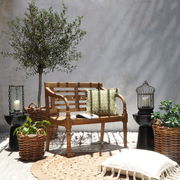 Holzgartenbank für zwei Personen in einem stilvollen Außenbereich, umgeben von Pflanzen und Dekorationen, seitliche Perspektive