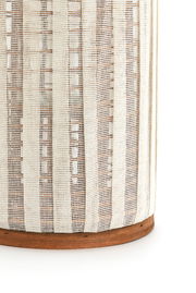 Nahaufnahme eines Windlichts mit einem gestreiften, gewebten Stoffdesign und einem Holzsockel, seitliche Perspektive