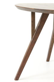 Nahaufnahme eines Esstisches mit runder Tischplatte und schrägen Holzbeinen, seitliche Perspektive.