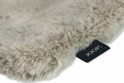 Nahaufnahme einer flauschigen, beigen Decke mit einem schwarzen Etikett, das 'JOOP!' zeigt.