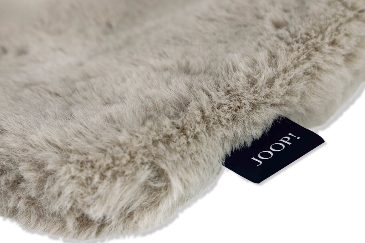 Nahaufnahme einer flauschigen, beigen Decke mit einem schwarzen Etikett, das 'JOOP!' zeigt.