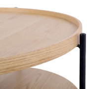 Close-up van een ronde salontafel met houten blad en zwart metalen onderstel, gezien vanaf de zijkant