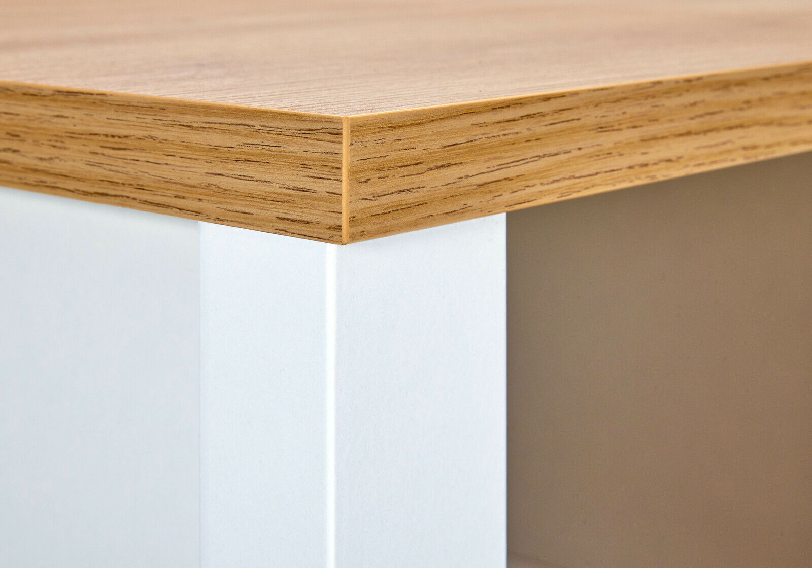 Nahaufnahme einer Ecke eines Kühlschrank-Umbau- oder Vorratsschranks mit Holzoptik-Oberfläche und weißem Korpus, Perspektive von schräg oben.