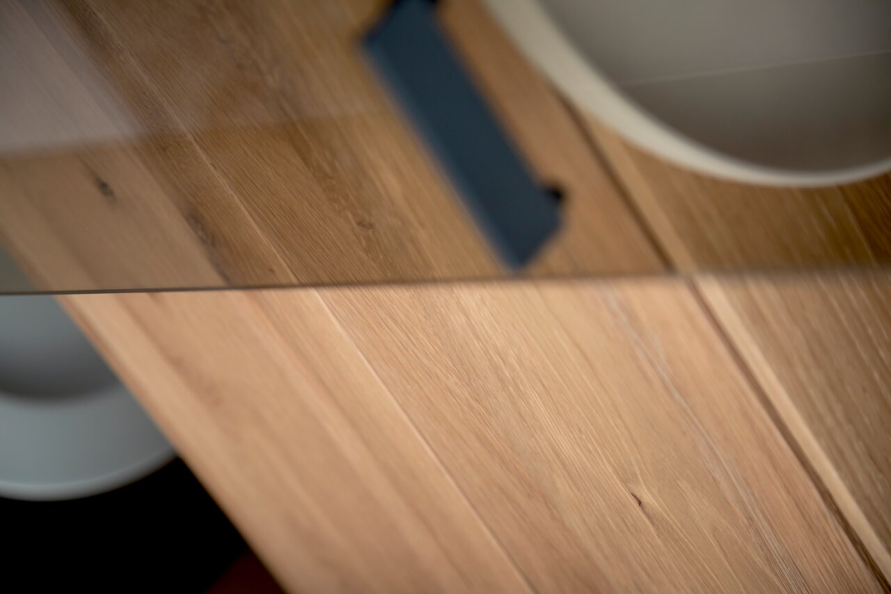 Nahaufnahme einer Vitrine mit Holzoberfläche und Glaselementen, aus der Vogelperspektive fotografiert.