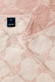 Nahaufnahme eines rosa Handtuchs mit floralem Muster und einem schwarzen Etikett mit der Aufschrift 'JOOP!'