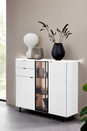 Modernes weißes Highboard mit Glastür und dekorativen Vasen, seitliche Perspektive