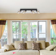 Deckenstrahler aus schwarzem Metall mit vier verstellbaren Leuchten, montiert an der Wohnzimmerdecke, Perspektive von unten.