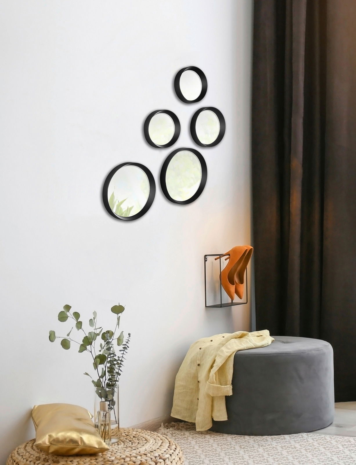 Fünf rund angeordnete Spiegel an einer weißen Wand, mit schwarzem Rahmen, in einem modernen Wohnambiente. Perspektive von der Seite.