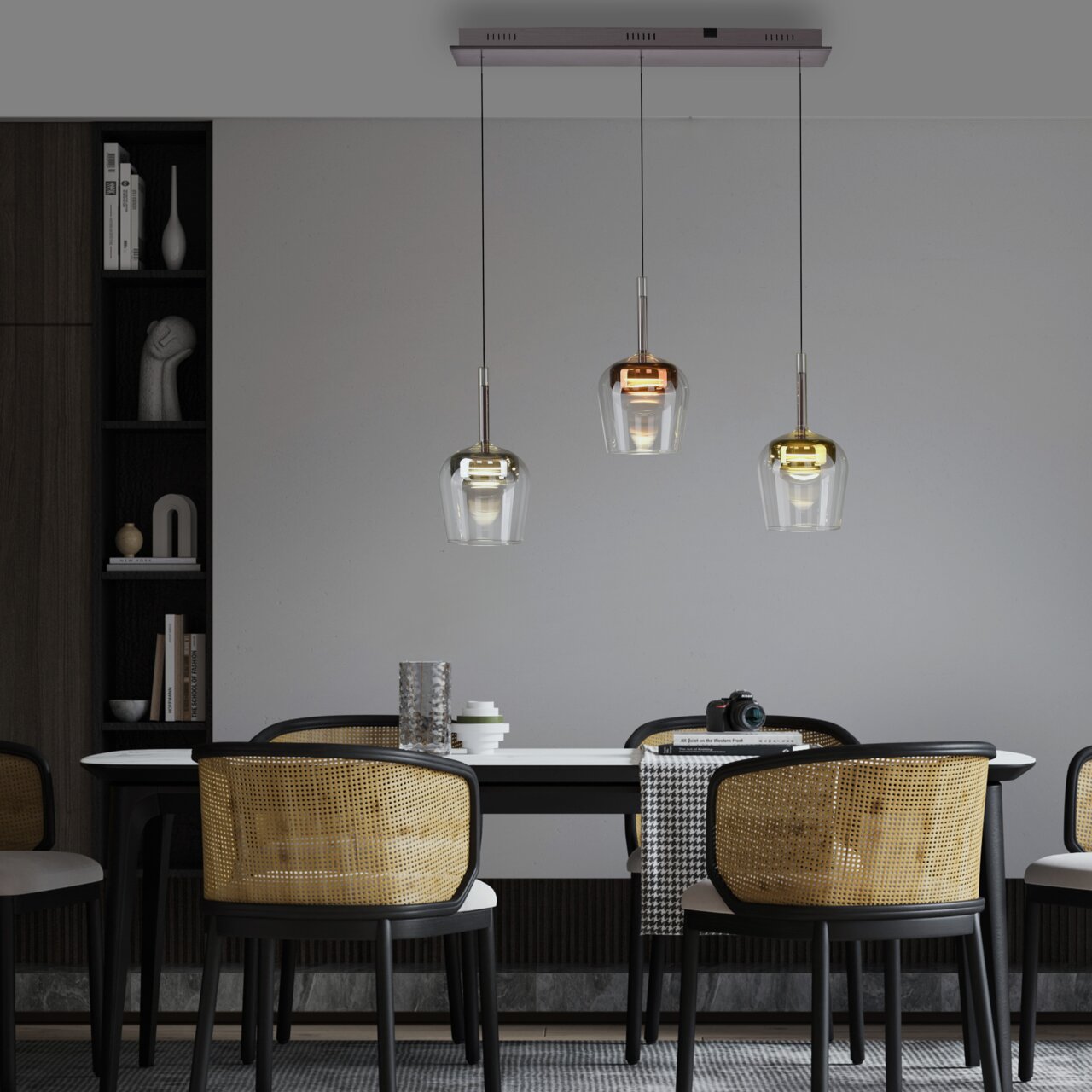 Moderne hanglamp Q-KON met drie hangende glazen elementen in verschillende metaaltinten boven een eettafel, gezien vanaf de zijkant.