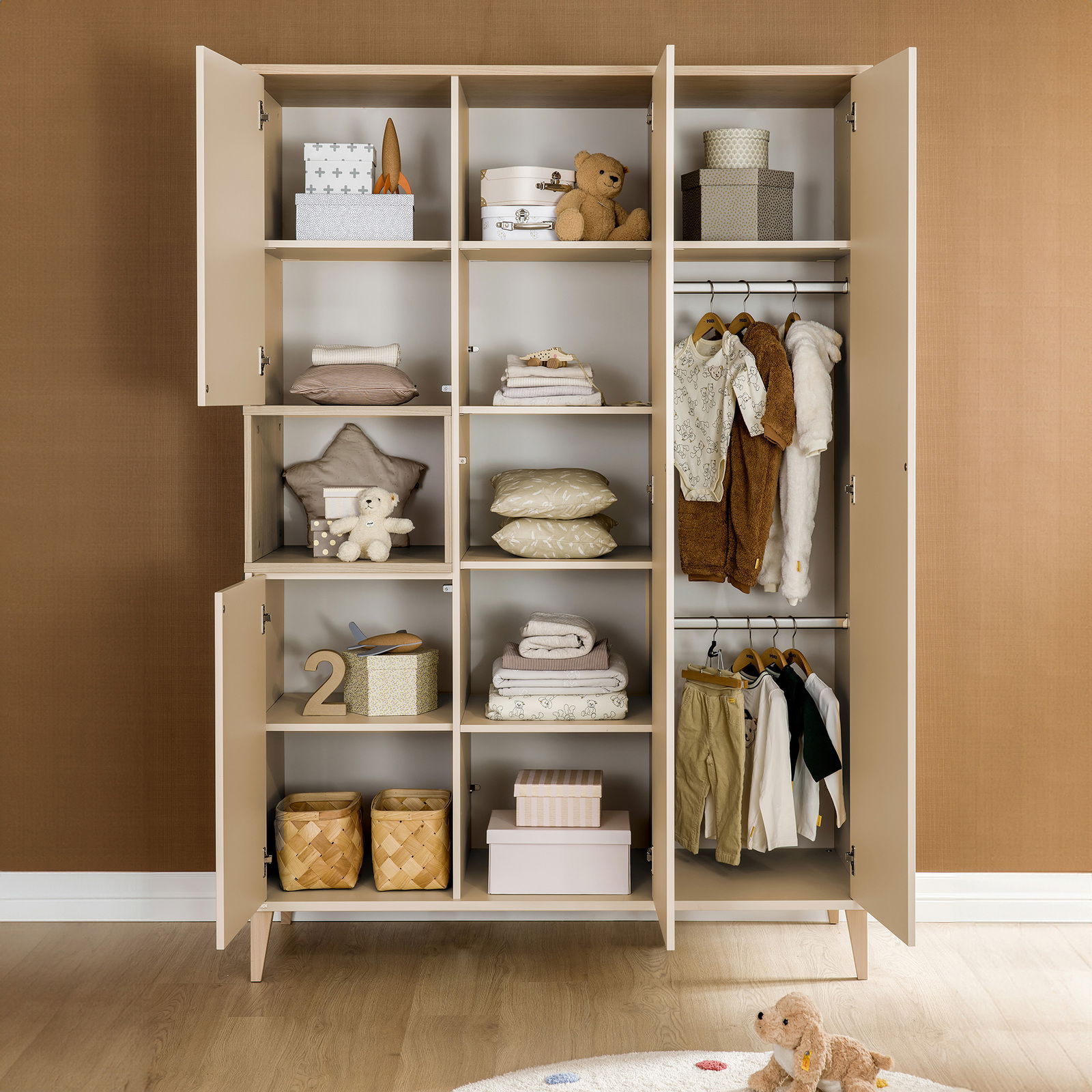 Offener Kleiderschrank mit vier Türen, gefüllt mit Kleidung, Spielzeug und Aufbewahrungsboxen, aus frontaler Perspektive.