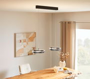 Moderne LED-Hängeleuchte mit zwei runden Leuchtringen, von der Decke hängend über einem Esstisch, seitliche Perspektive.