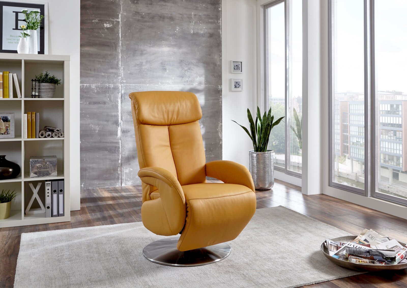 Moderne gele tv-fauteuil in een lichte woonkamer met grote ramen, zijaanzicht.