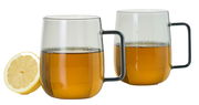 Zwei transparente Tassen mit schwarzem Griff, gefüllt mit Tee, im Vordergrund eine halbe Zitrone, seitliche Perspektive.