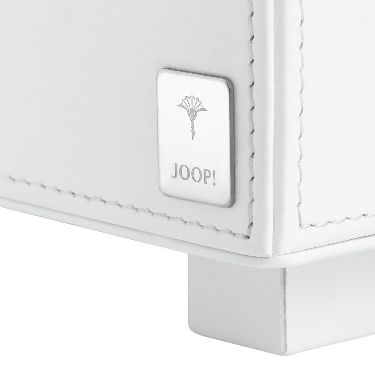 Nahaufnahme eines weißen Tabletts mit einem Joop!-Logo auf einer Metallplakette, perspektivisch von der Seite aufgenommen.