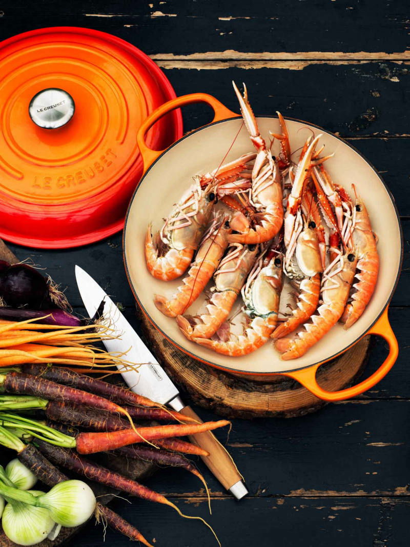 Gourmet Profitopf 30cm in Ofenrot mit Meeresfrüchten gefüllt, von oben fotografiert, umgeben von frischem Gemüse und einem Messer.