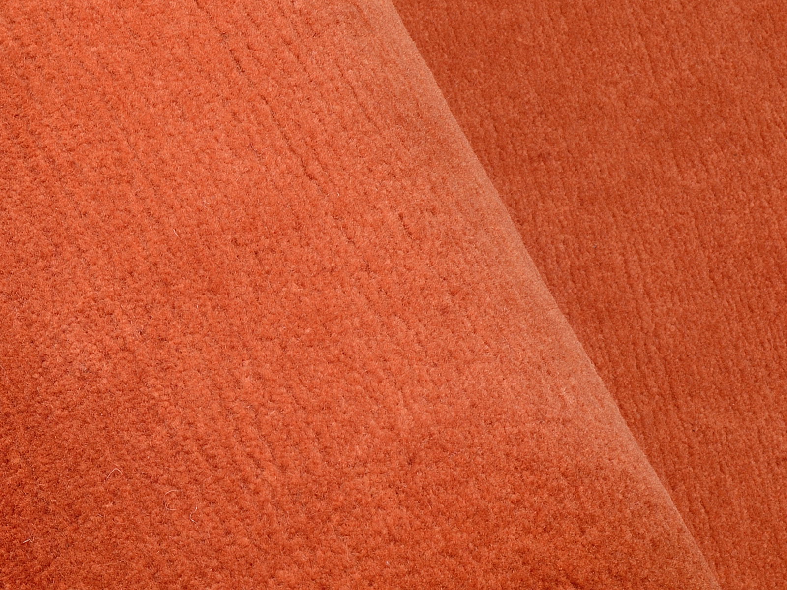 Nahaufnahme eines orangefarbenen Wollteppichs mit weicher Textur.
