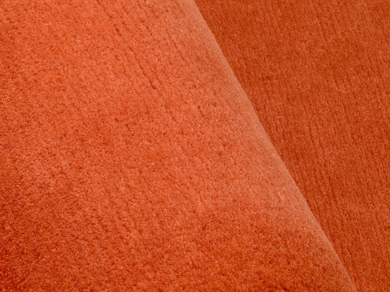 Nahaufnahme eines orangefarbenen Wollteppichs mit weicher Textur.