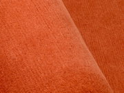 Nahaufnahme eines orangefarbenen Wollteppichs mit weicher Textur.