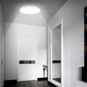Moderne ronde plafondlamp met helder wit licht in een minimalistische hal, gezien vanuit een lage hoek omhoog naar het plafond