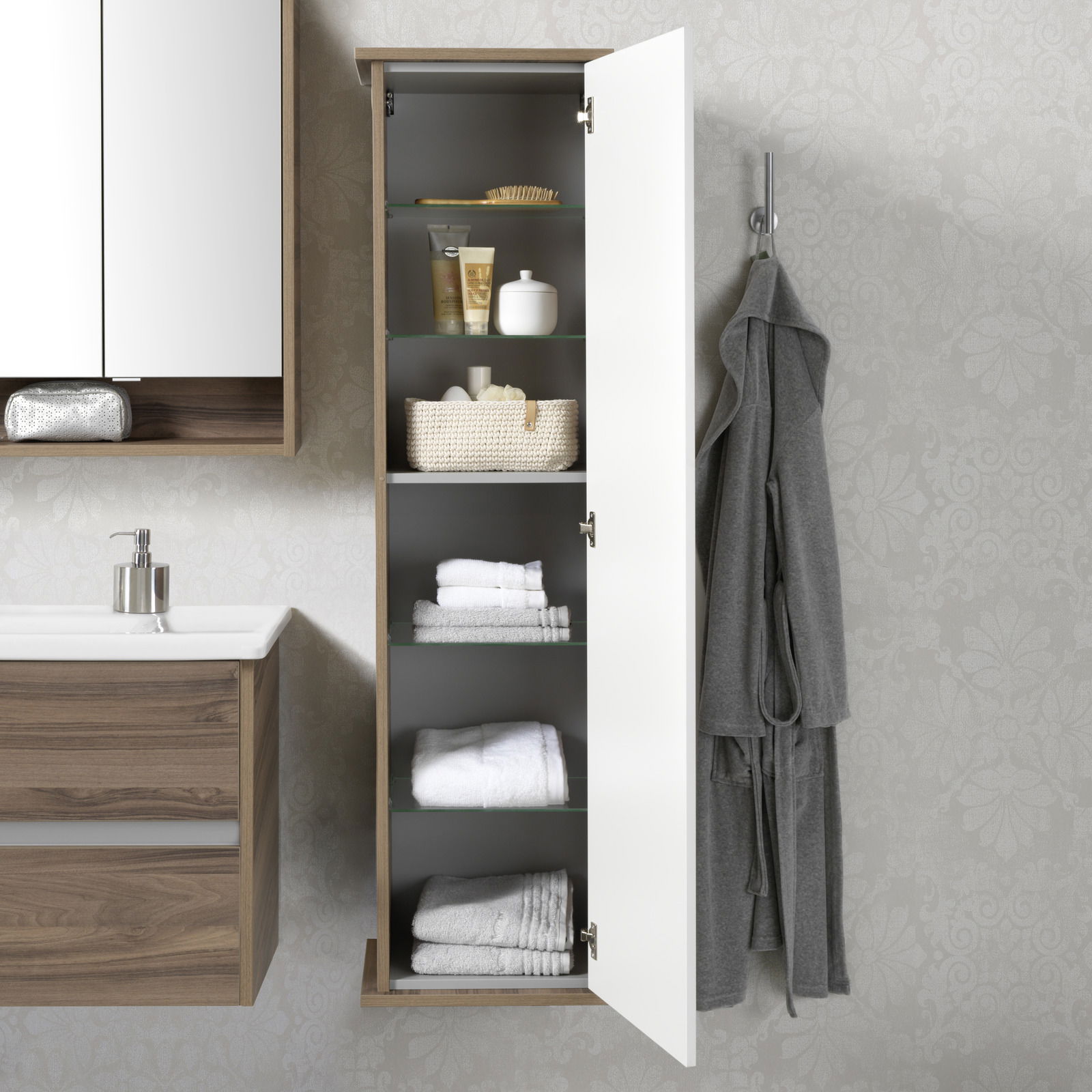 Hochschrank mit geöffneter Tür, gefüllt mit Handtüchern und Pflegeprodukten, von vorne betrachtet.