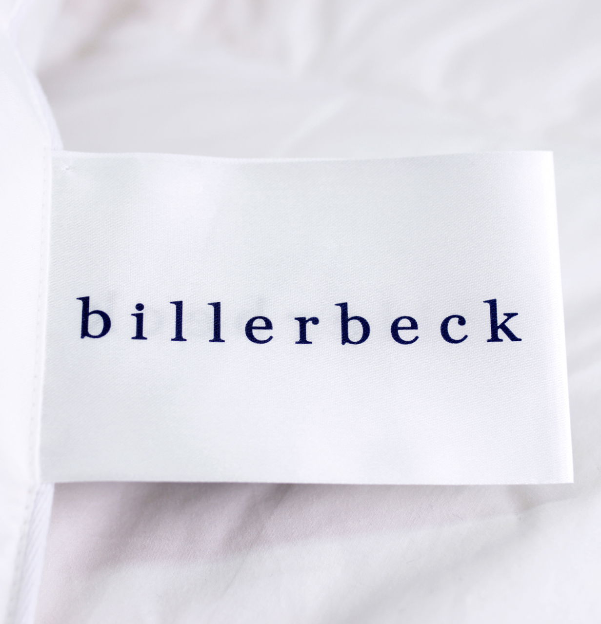 Nahaufnahme eines Etiketts mit der Aufschrift 'billerbeck' auf einer weißen Daunendecke.