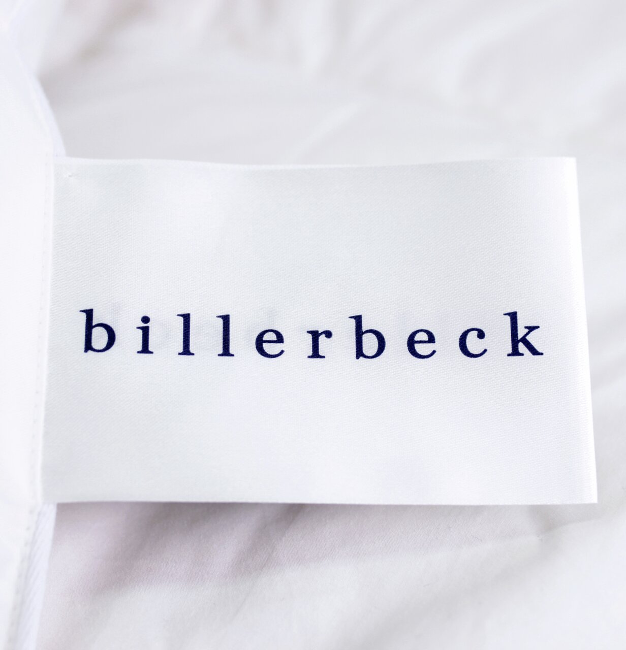 Nahaufnahme eines Etiketts mit der Aufschrift 'billerbeck' auf einer weißen Daunendecke.