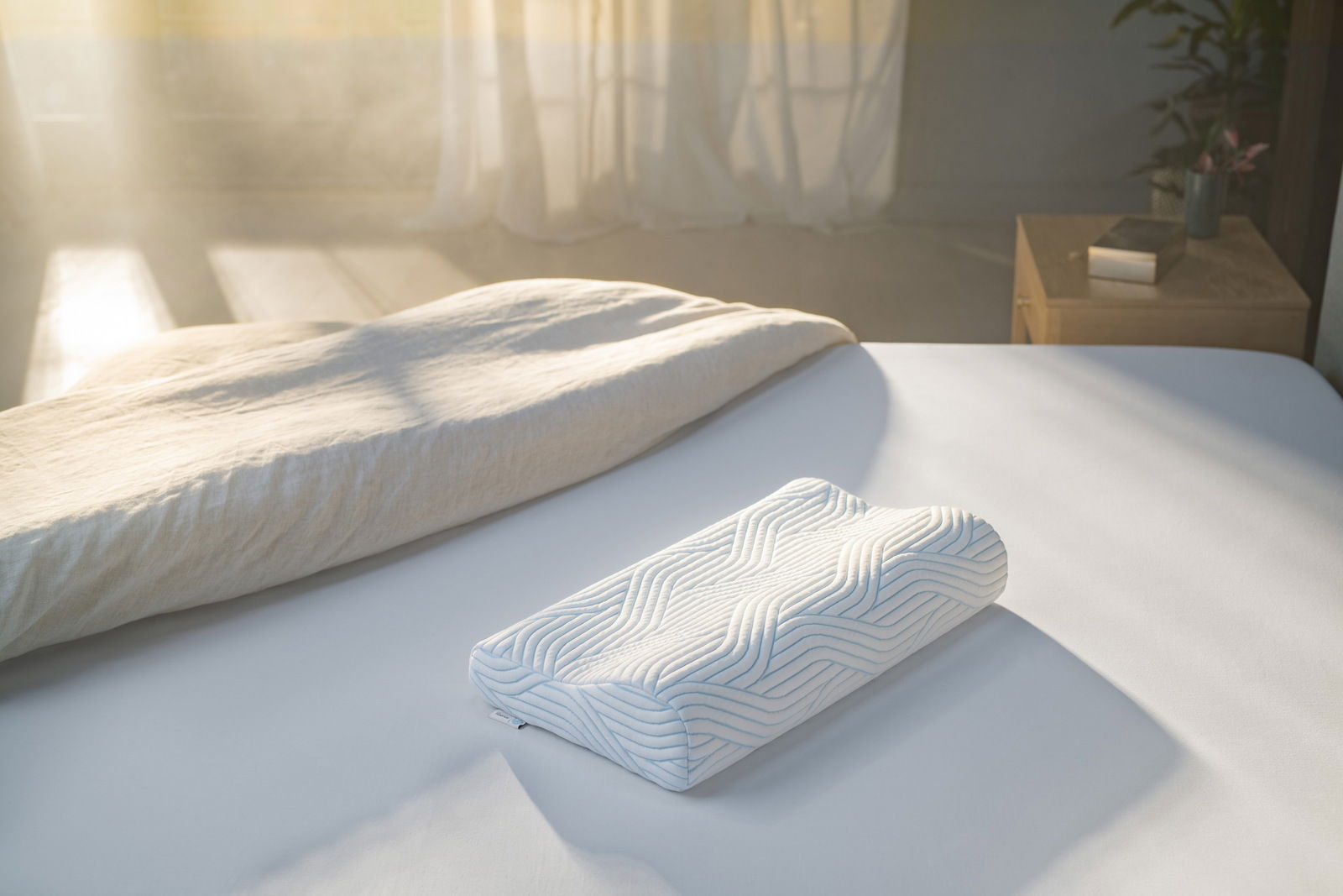 Tempur Schlafkissen SHAPE Schlafkissen 61 x 31 cm auf einem Bett, seitliche Perspektive, mit Sonnenlicht im Hintergrund