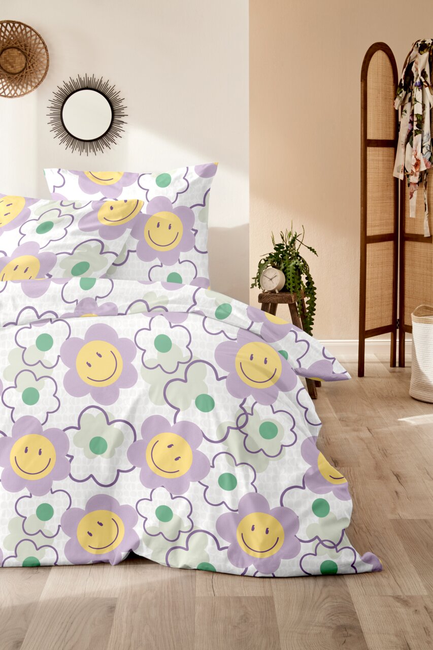 Bettwäsche mit fröhlichem Blumenmuster in Lila, Gelb und Grün, fotografiert aus einer seitlichen Perspektive im Schlafzimmer.