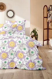 Bettwäsche mit fröhlichem Blumenmuster in Lila, Gelb und Grün, fotografiert aus einer seitlichen Perspektive im Schlafzimmer.