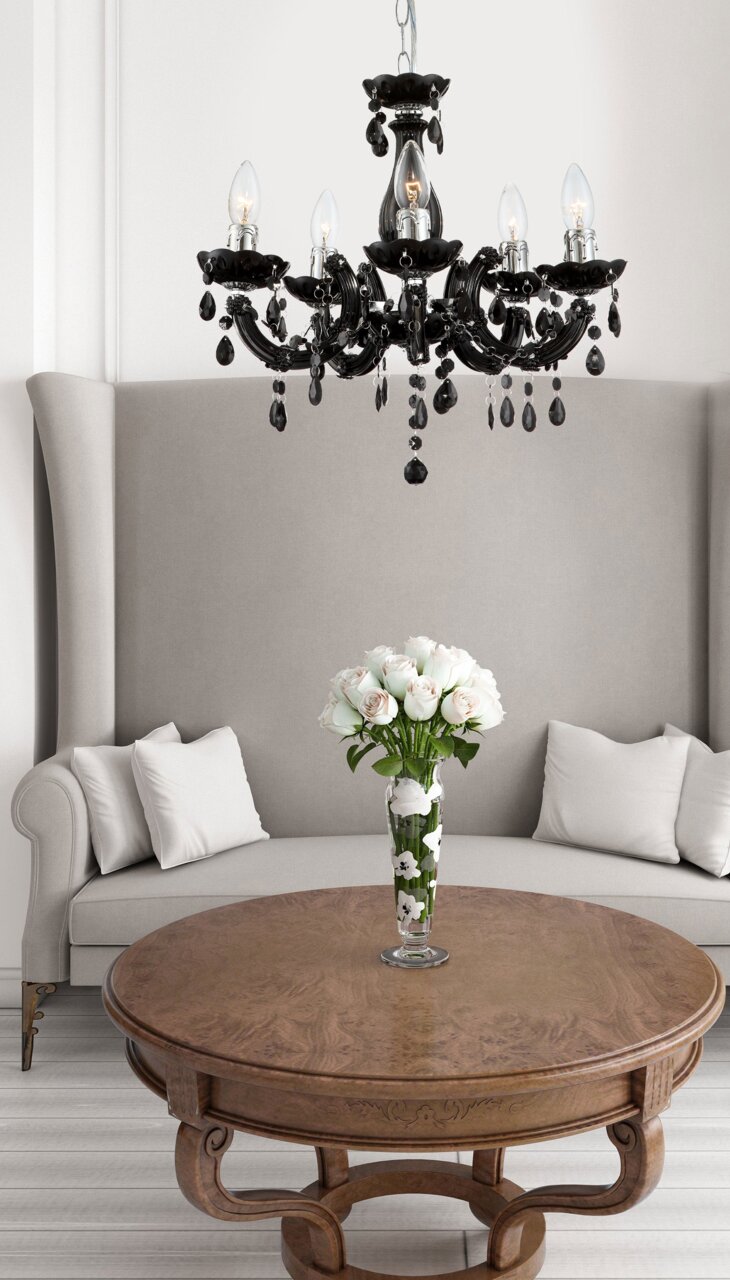 Eleganter schwarzer Kronleuchter mit sechs Armen und dekorativen Kristallen, hängend über einem runden Holztisch in einem stilvollen Wohnzimmer. Perspektive von unten.