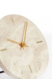 Nahaufnahme einer eleganten Uhr mit einem Zifferblatt aus hellem Stein und goldenen Zeigern, leicht von der Seite betrachtet.