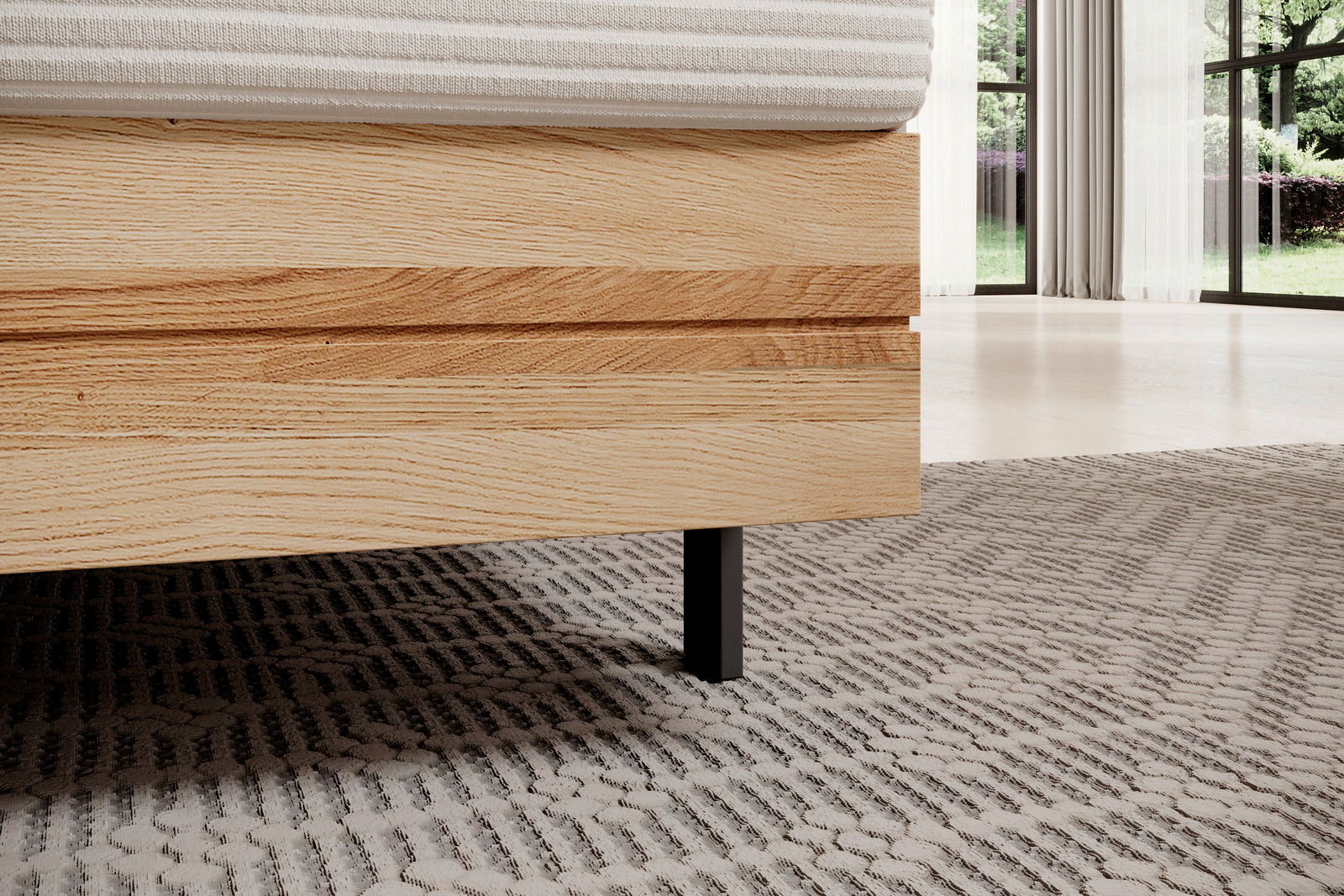 Nahaufnahme eines Boxspringbettes mit Holzrahmen und schwarzem Bein, seitliche Perspektive.