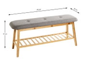 Gepolsterte Sitzbank mit grauem Stoffbezug und Bambusgestell mit Ablage, Maße ca. 100 x 30 x 44 cm, in schräger Seitenansicht von vorne freigestellt auf weißem Hintergrund