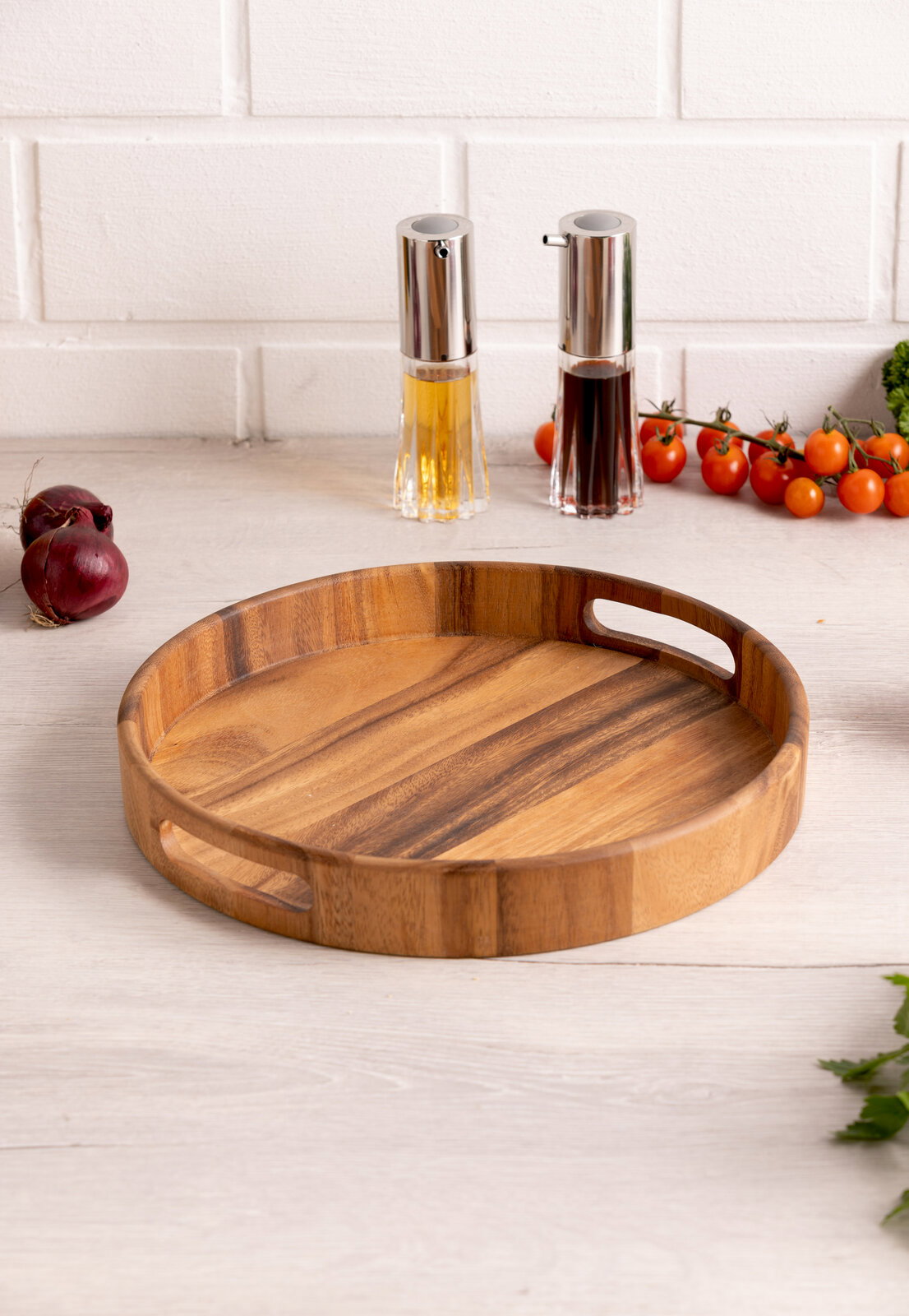 Rundes Holztablett mit Griffen, auf einem Tisch in einer Küchenumgebung, aus der Perspektive von schräg oben fotografiert.