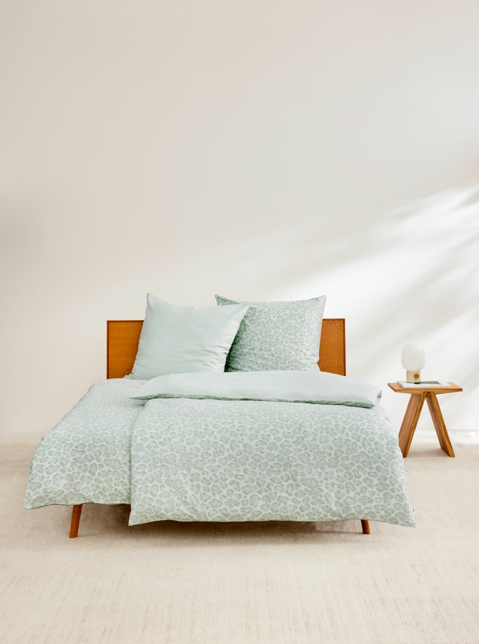 s.Oliver Bettwäsche Satinbettwäsche 135x200cm in hellem Grün mit dezentem Muster, auf einem Holzrahmenbett präsentiert, seitliche Perspektive