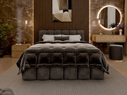 Luxuriöses Polsterbettgestell in einem stilvoll eingerichteten Schlafzimmer, frontal betrachtet. Das Bett ist mit einer dunklen, gesteppten Decke und mehreren Kissen ausgestattet. Im Hintergrund sind eine moderne Wandverkleidung, ein runder beleuchteter S