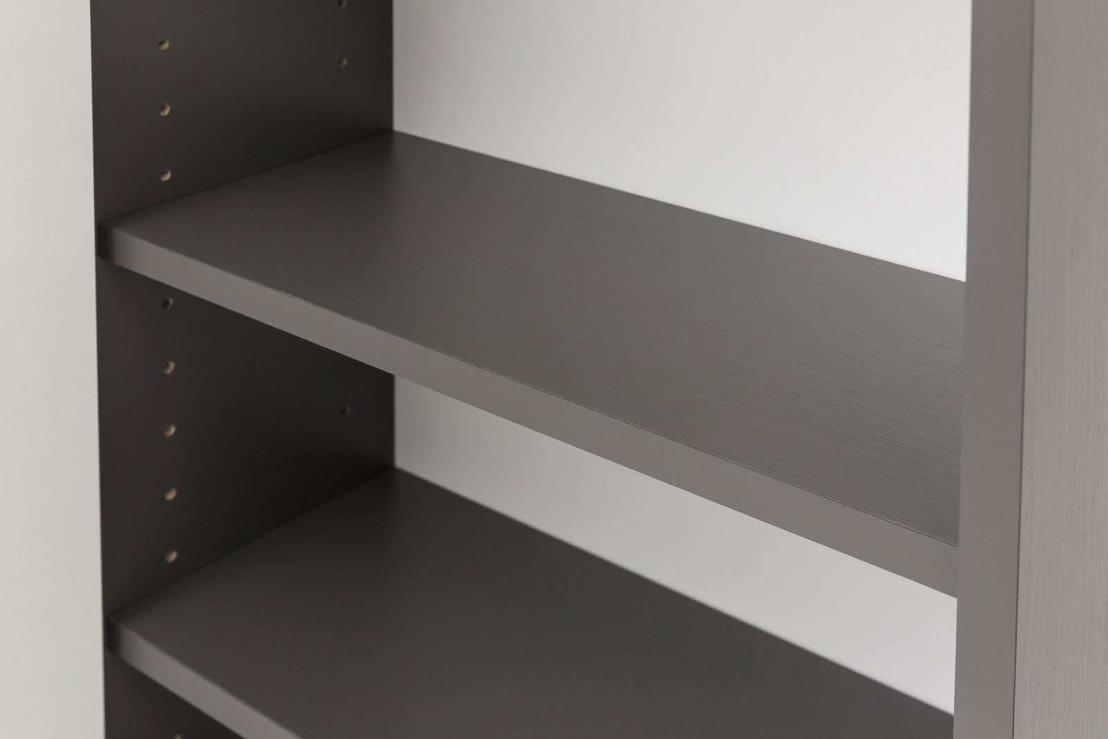 Nahaufnahme eines grauen Hängeschranks mit verstellbaren Regalböden, seitliche Perspektive