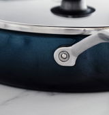 Nahaufnahme einer petrolfarbenen Servierpfanne mit silbernem Griff und Deckel, seitliche Perspektive.