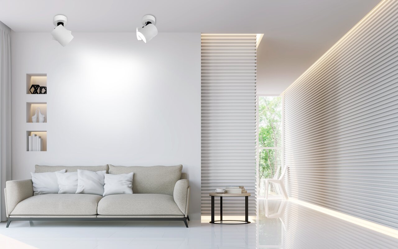 Moderner Wohnraum mit zwei weißen LED-Spots an der Decke, die den Raum beleuchten. Perspektive von vorne auf die Spots gerichtet.