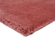 Nahaufnahme eines weichen, rosafarbenen Teppichs mit flauschiger Textur, gezeigt aus einer seitlichen Perspektive.