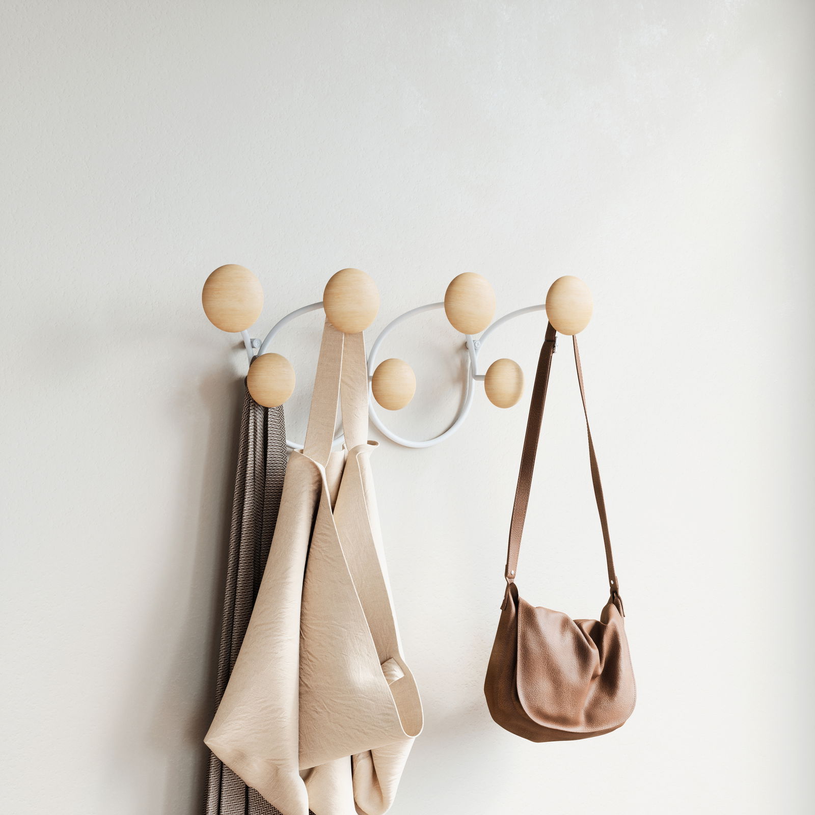 Moderne Wandgarderobe mit runden Holzkugeln, an der Taschen und Kleidung hängen. Seitliche Perspektive.