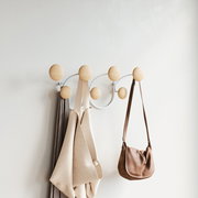 Moderne Wandgarderobe mit runden Holzkugeln, an der Taschen und Kleidung hängen. Seitliche Perspektive.