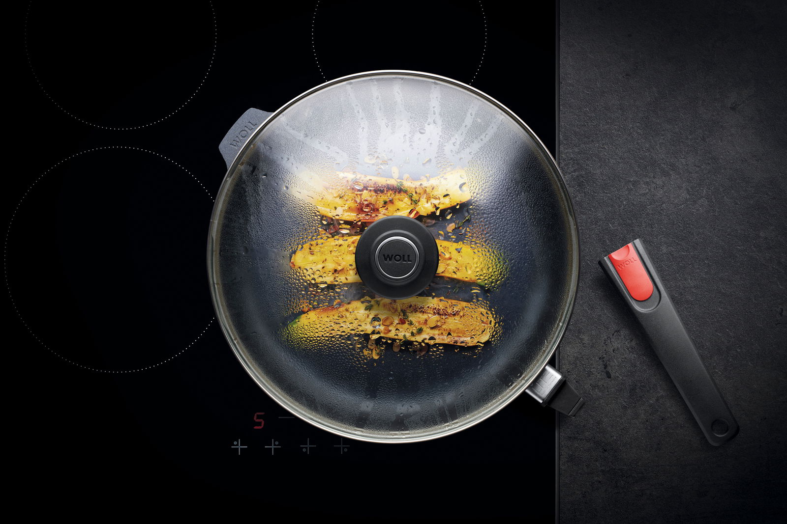 Woll Guss-Hochrandpfanne DIAMOND LITE Guss-Hochrandpfanne 32cm Diamo mit Glasdeckel, von oben fotografiert, auf einem Herd mit abnehmbarem Griff.