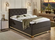 Boxspringbett in einem gemütlichen Schlafzimmer mit modernem Design, seitliche Perspektive