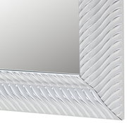 Nahaufnahme eines Spiegels mit wellenförmigem Rahmen, perspektivisch von der Seite aufgenommen.