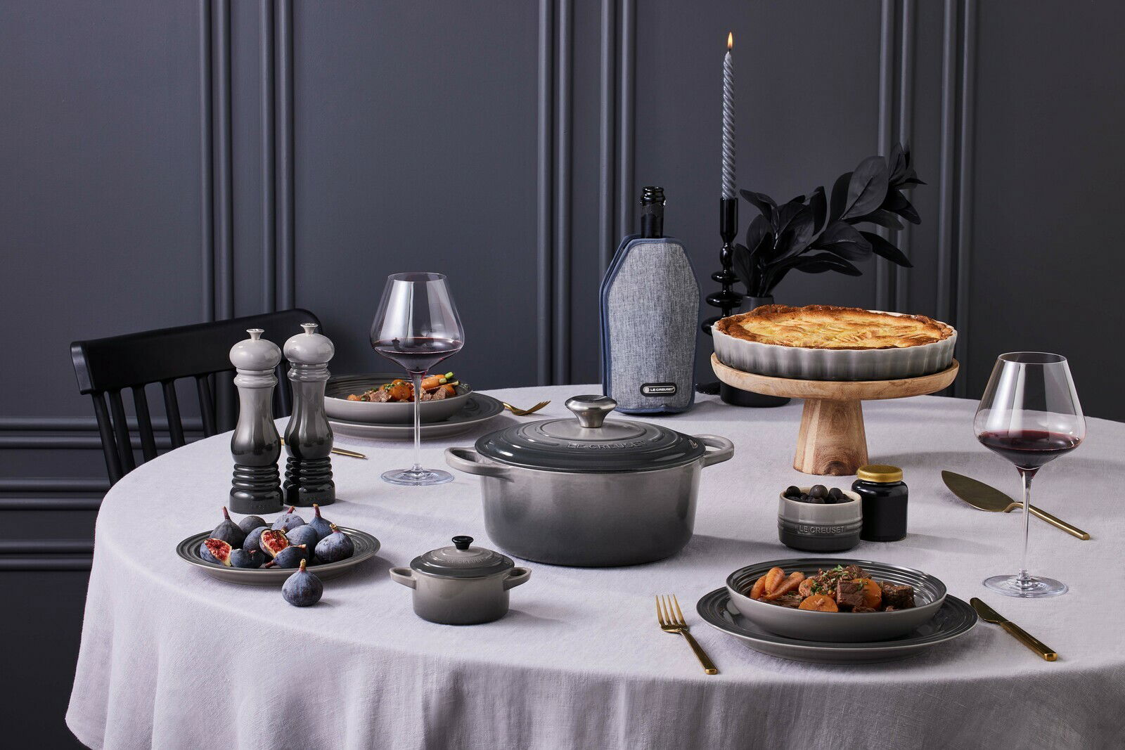 Elegante Tischszene mit einer grauen Salzmühle im Vordergrund, umgeben von stilvollem Geschirr und einer gedeckten Tafel, aus seitlicher Perspektive.