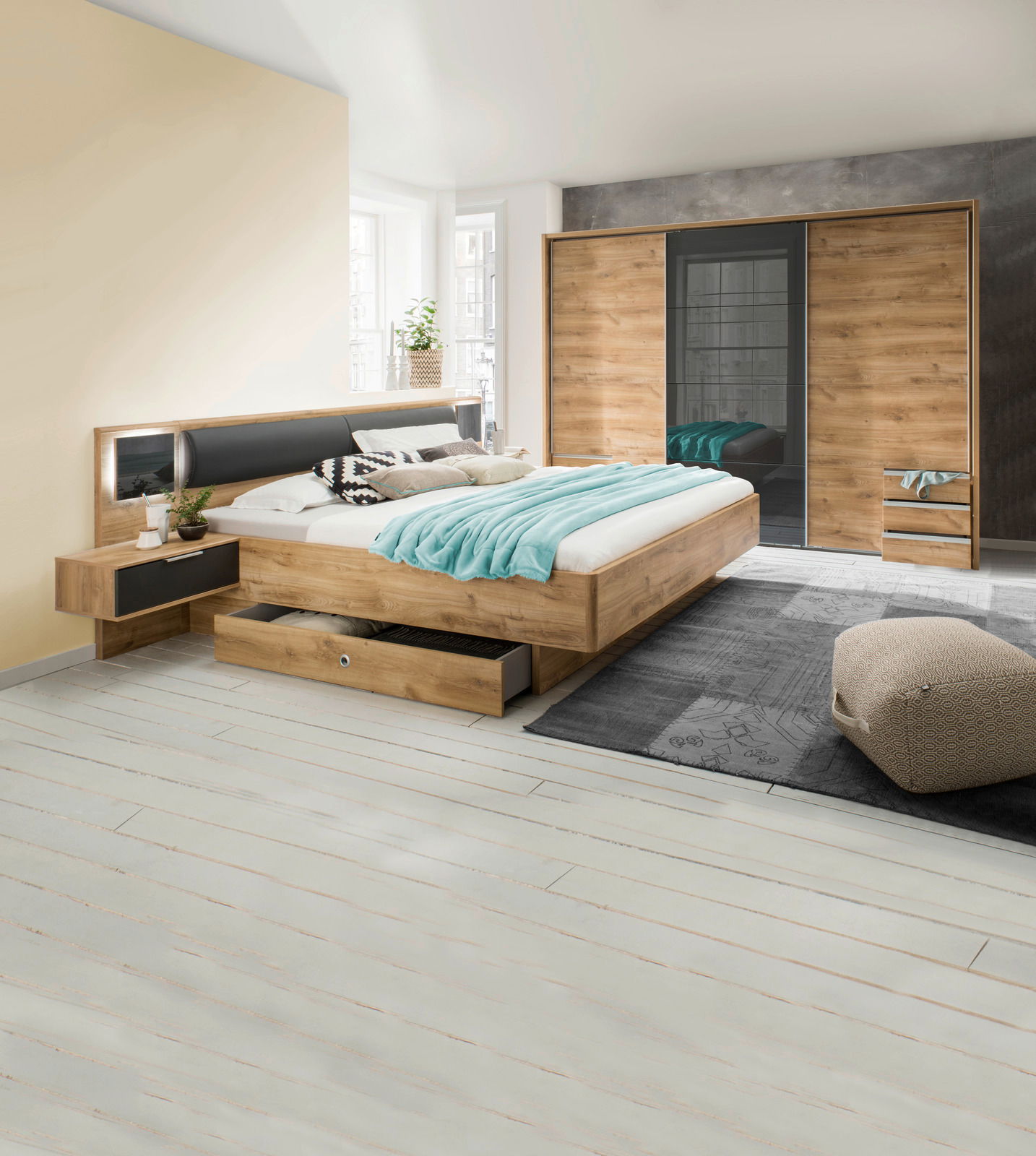 Moderne Schlafzimmermöbel mit einem dreitürigen Schwebetürenschrank, einem Bett mit integrierten Schubkästen und Nachttischen in Holzoptik. Perspektive: seitliche Ansicht des Schlafzimmers.